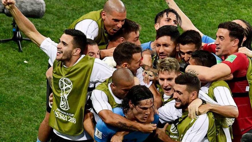 Los jugadores uruguayo, entre ellos el céltico Maxi Gómez (izquierda) se abalanzan sobre Cavani para celebrar su segundo gol. // AFP