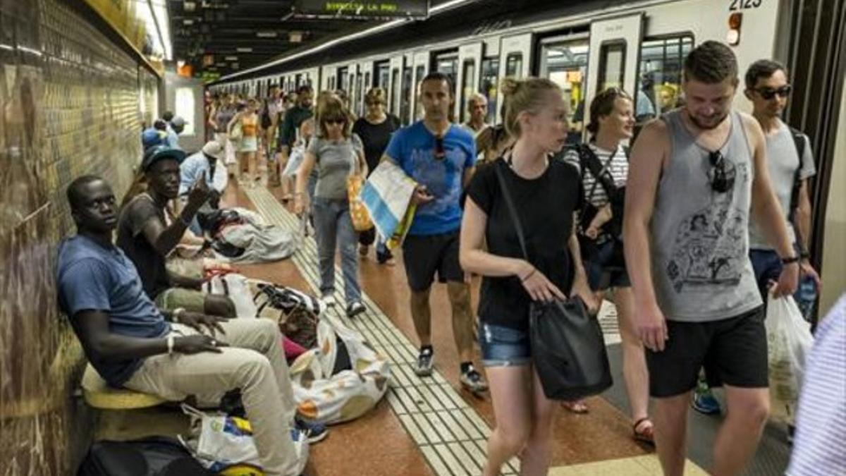 Pasajeros de la línea 4 y manteros en un andén de la parada de Barceloneta, ayer.