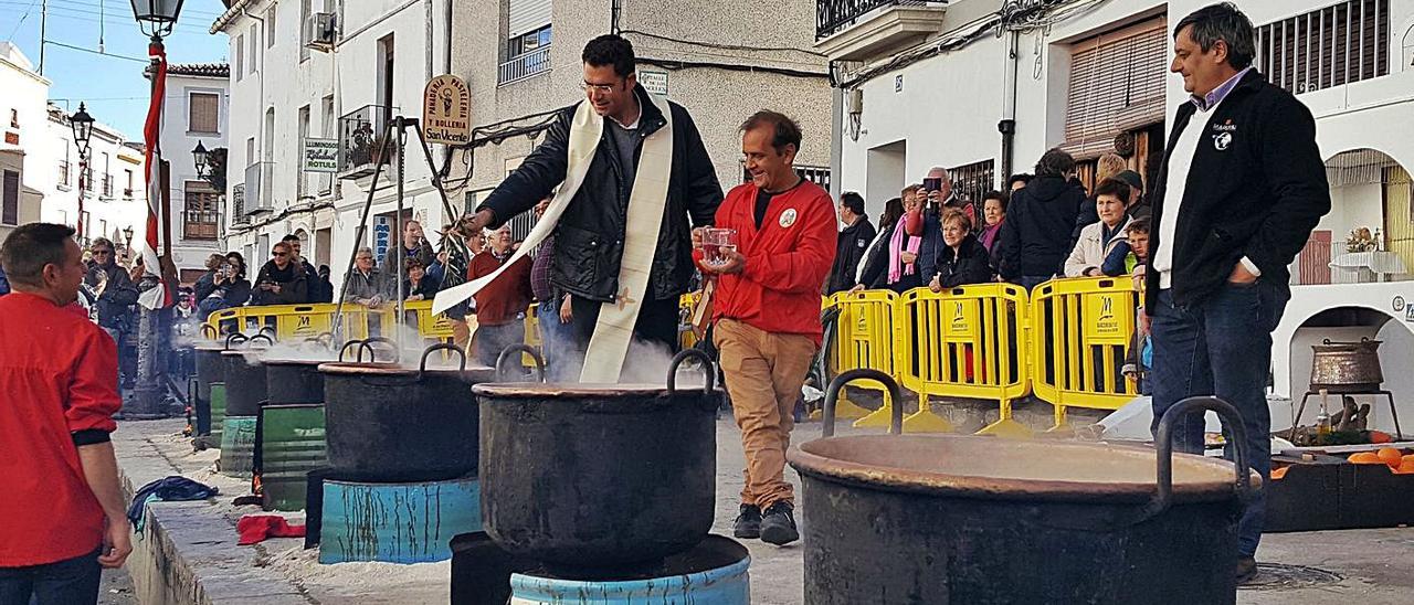 El párroco bendice las calderas, ante la mirada de decenas de vecinos y vecinas de Oliva. | MIQUEL FONT