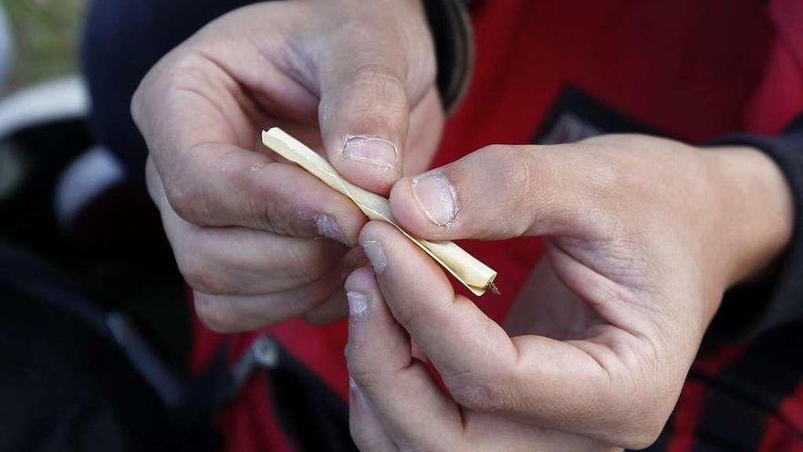 Un joven se prepara un porro.