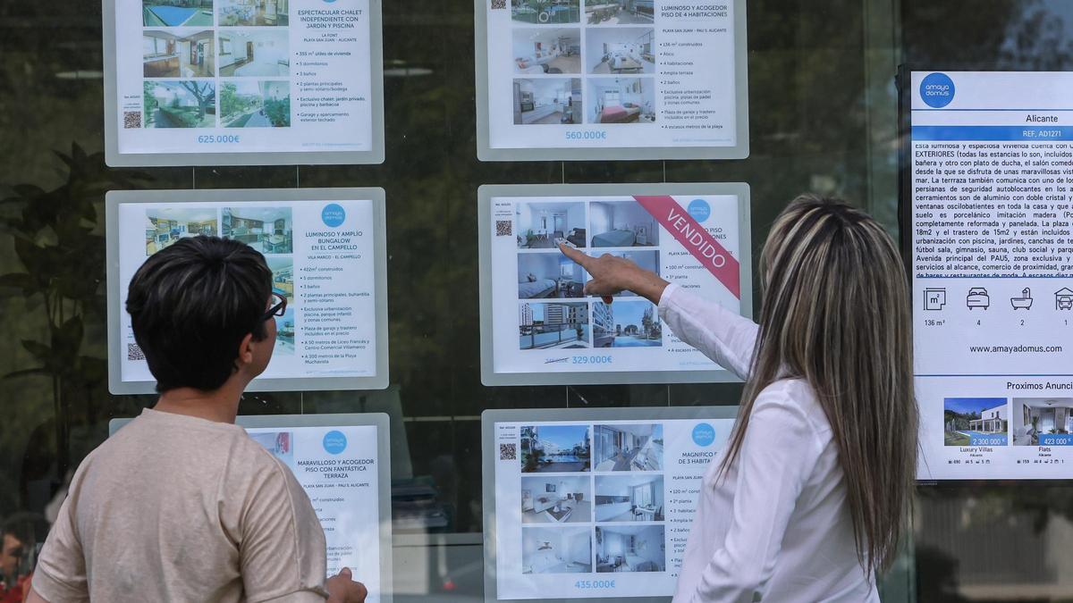Dos personas consultan las ofertas de una inmobiliaria de Alicante.