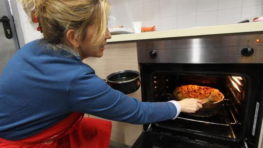 Mercedes Pérez Álvarez introduce el plato en el horno.