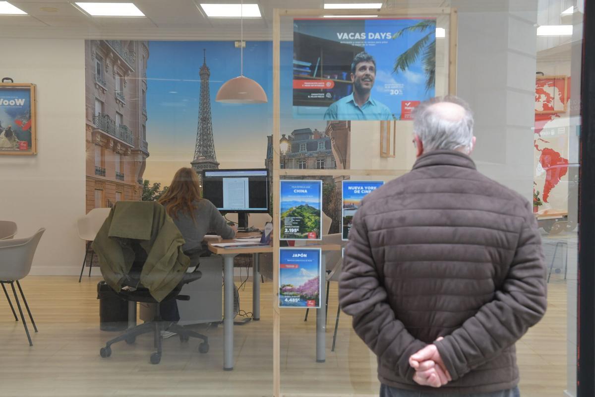 Un vecino ojea los carteles de una agencia de viajes en A Coruña.