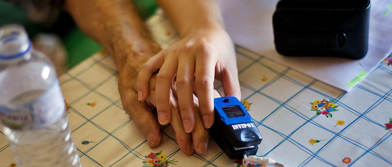 Personal sanitario controla la saturación de oxígeno a un paciente en su domicilio.