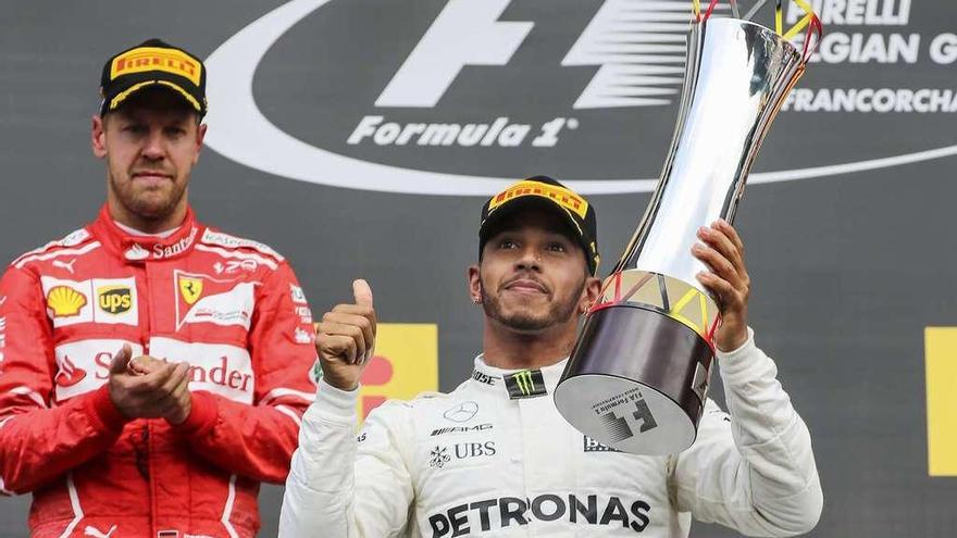 Hamilton recoge el trofeo al ganador en el podio belga aplaudido por su rival Sebastian Vettel.