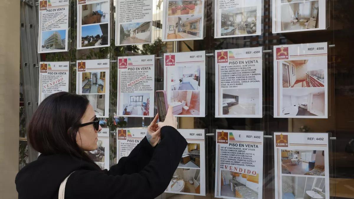 Una joven observas las ofertas de una inmobiliaria en imagen de archivo.