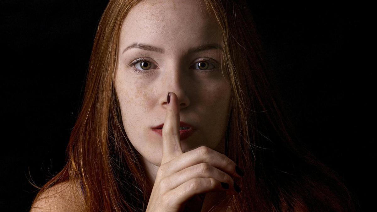 Una mujer hace el gesto del silencio.