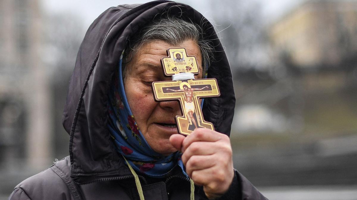 Una mujer religiosa sostiene una cruz mientras reza en la plaza de la Independencia en Kiev en la mañana del 24 de febrero de 2022.