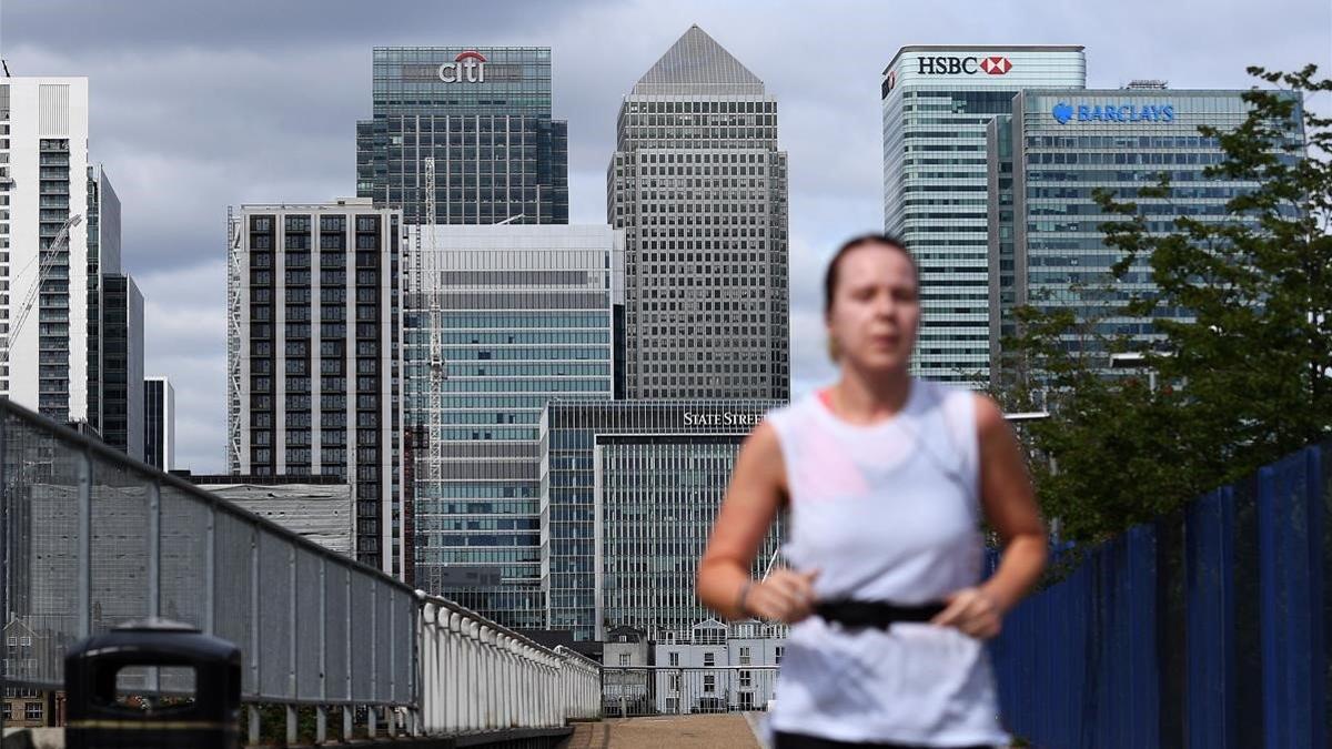 Una mujer corre por el distrito financiero de Londres, cuyas oficinas siguen vacías de trabajadores.