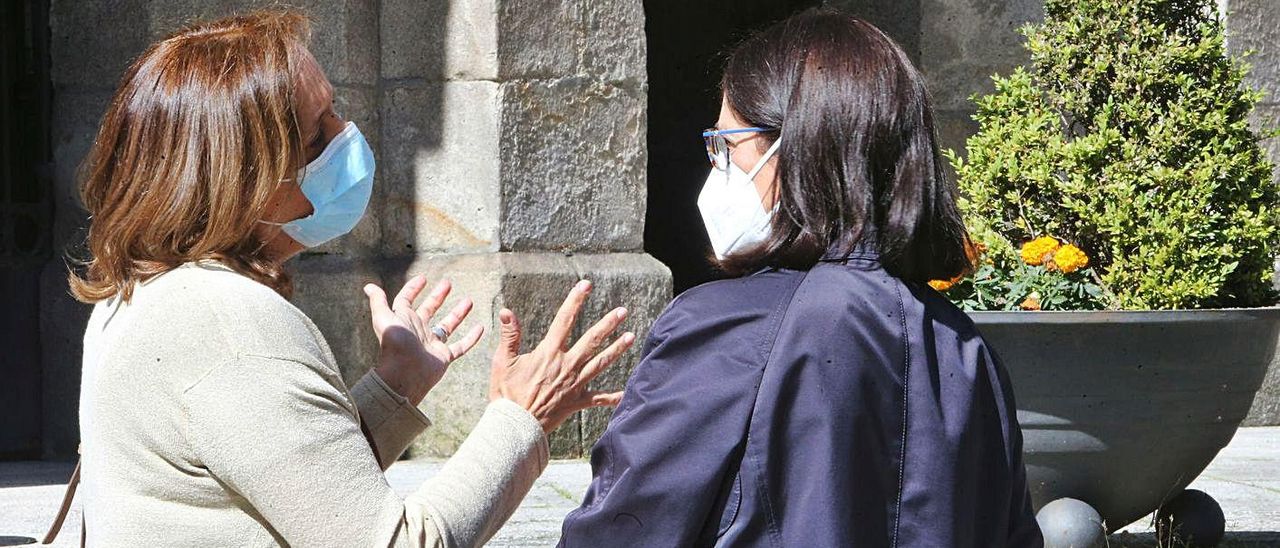 Dos mujeres con mascarilla hablan en la calle.