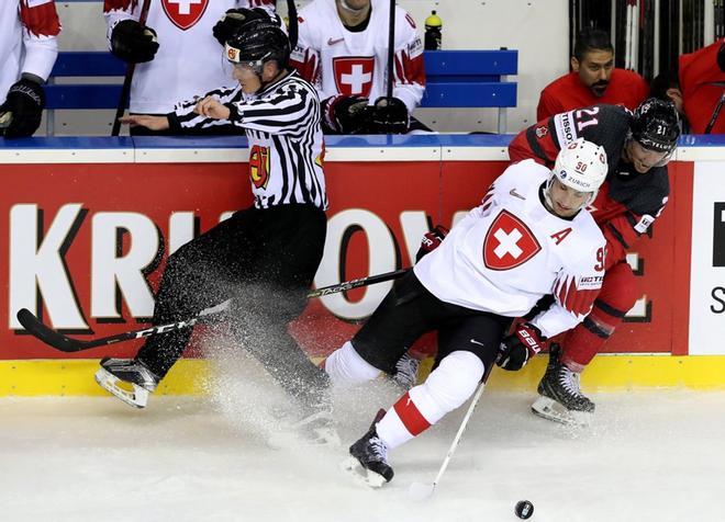 El canadiense Mathieu Joseph (dcha) pelea por el disco con el suizo Roman Josi (c), durante el partido de cuartos de final del Campeonato del Mundo de Hockey sobre hielo en el Steel Arena de Kosice (Eslovaquia).