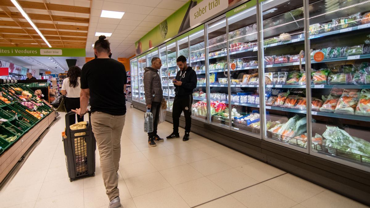 Varias personas hacen la compra en un supermercado.