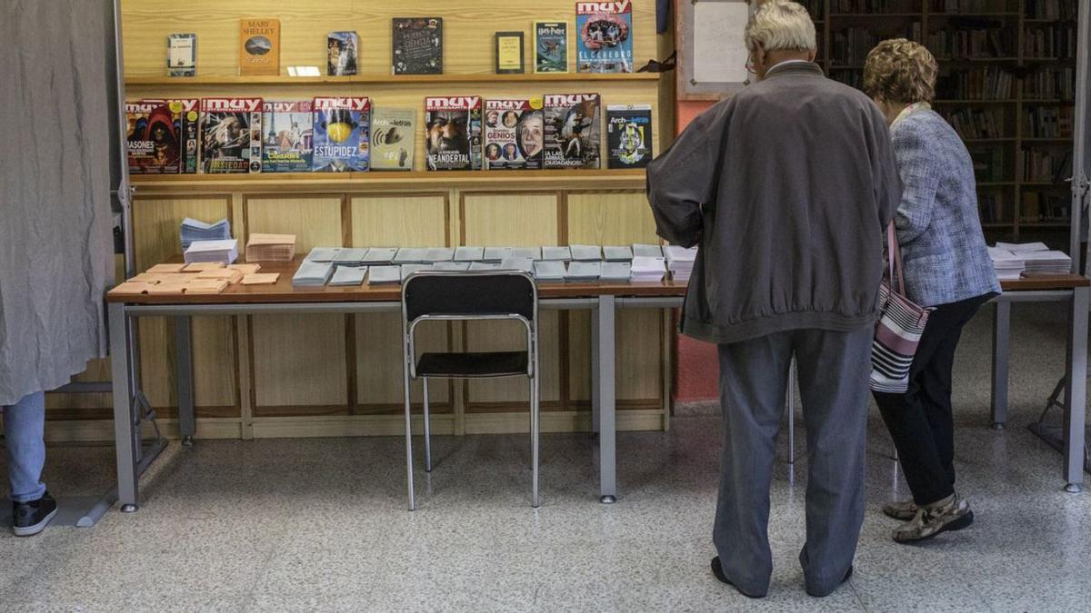 Dos personas cogen las papeletas para votar en las últimas elecciones en Castilla y León.