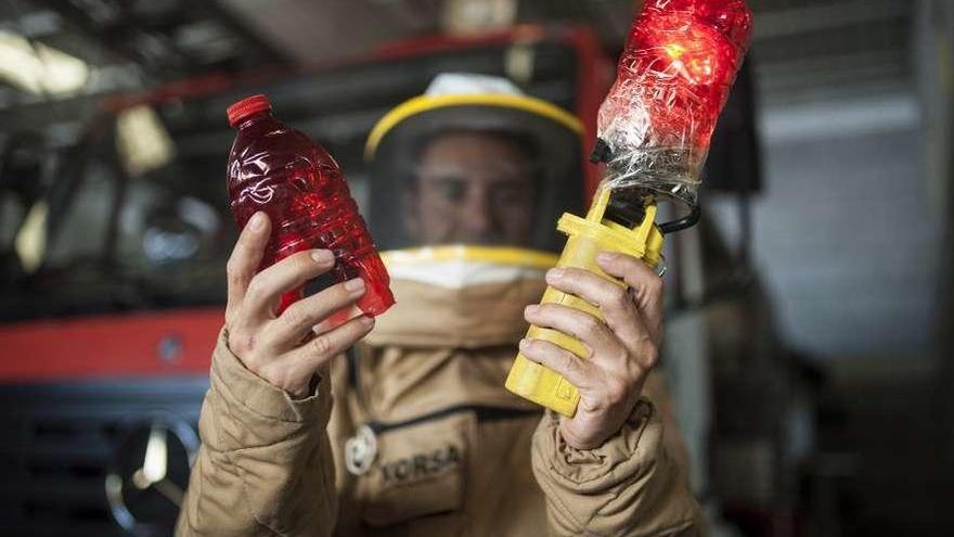 Un bombero con el traje de protección muestra la luz infrarroja que improvisan con botellas. // Brais Lorenzo