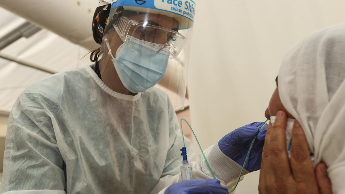 Una enfermera, equipada con material de protección, toma una muestra a un paciente