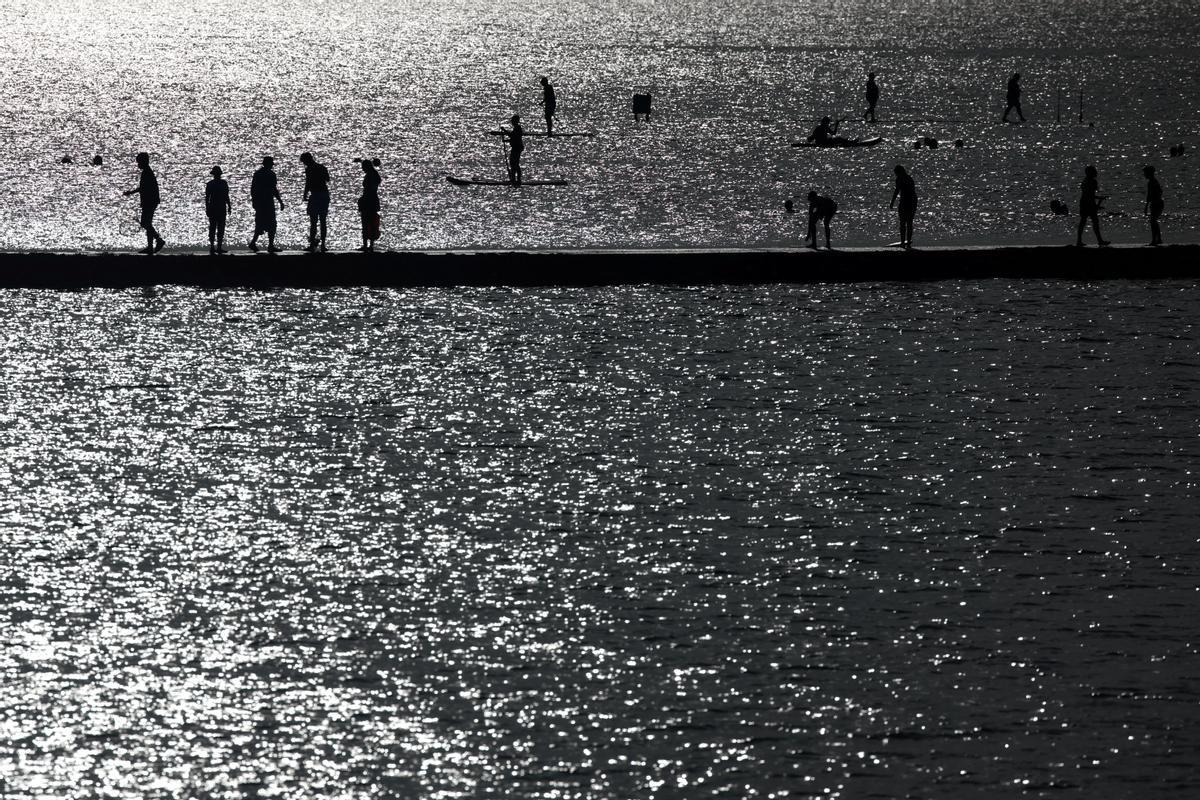 Un grupo de gente camina sobre el límite de una zona para baño en el mar en Margate, Gran Bretaña