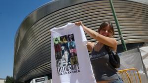 Una mujer sujeta una camiseta de merchandaising, en los alrededores del Estadio Santiago Bernabéu, este martes.