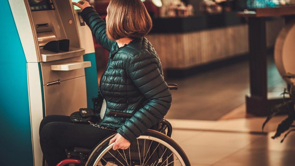 Una mujer con discapacidad en el cajero automático de una entidad.