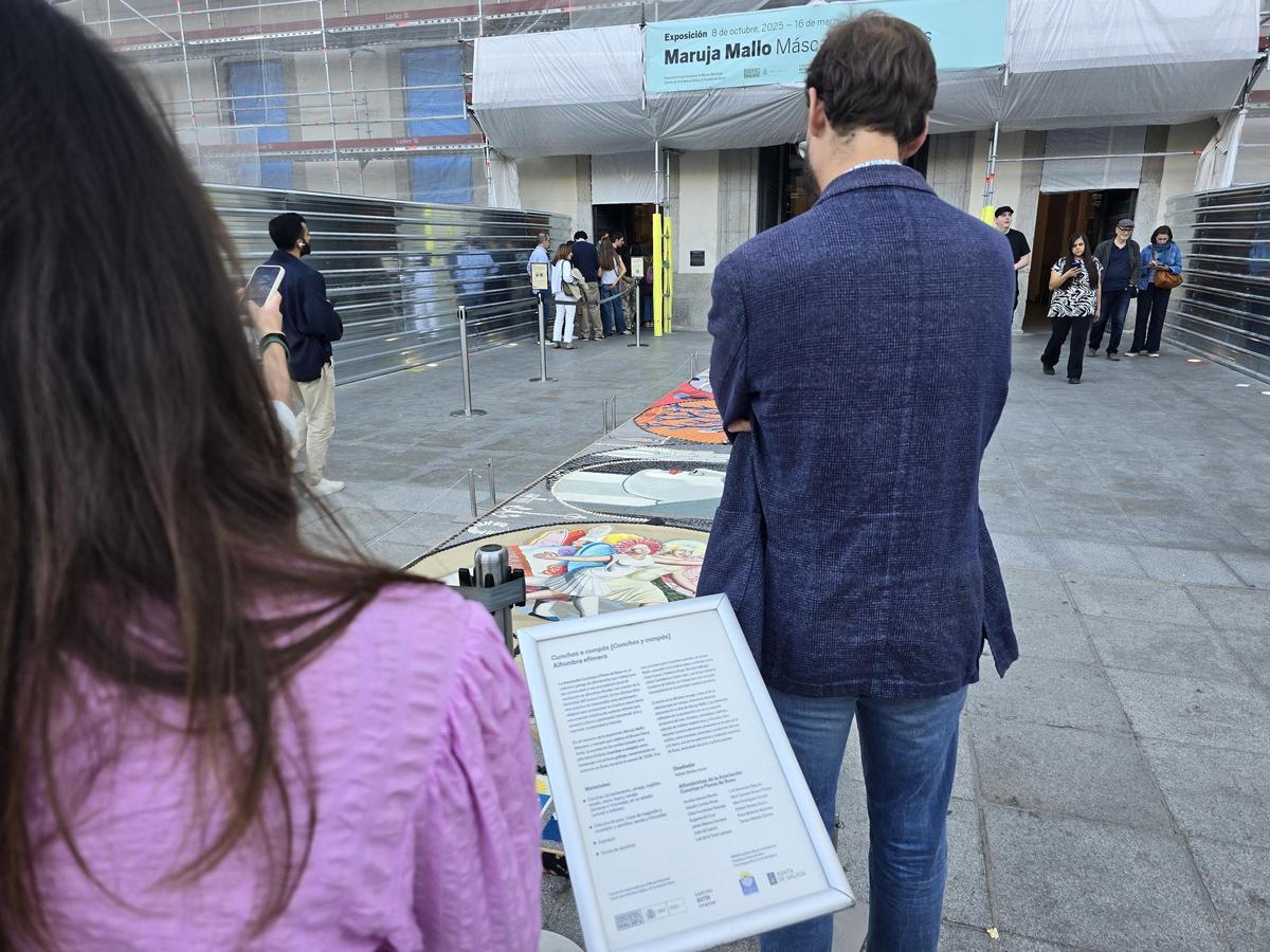 Público contemplando la alfombra y leyendo el cartel informativo sobre ella.