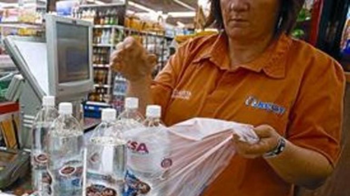 Una cajera de un supermercado distribuye una compra en bolsas.