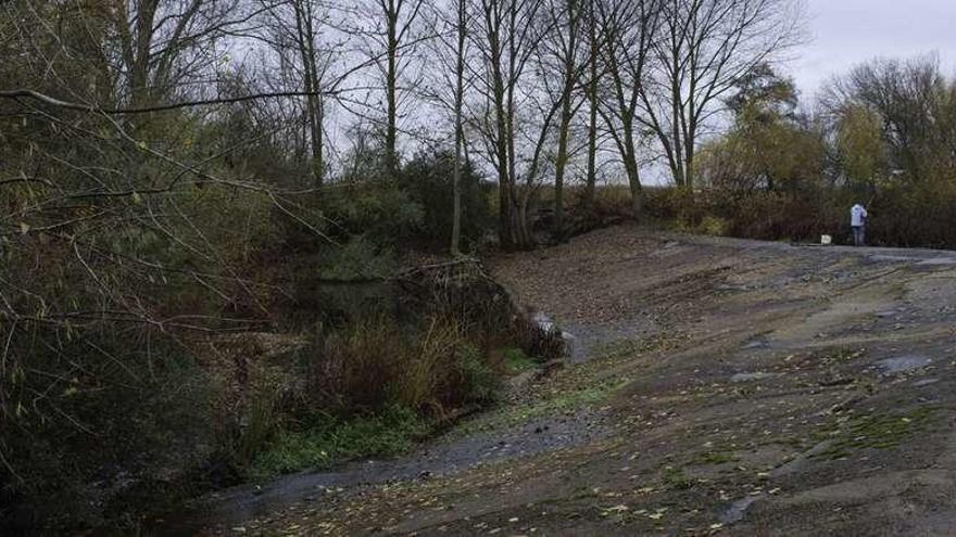 Un pescador en la presa sobre el río Órbigo de la que parte la Ría de Don Felipe hacia Benavente. Una frondosa e intrincada vegetación bloquea el curso natural del agua .