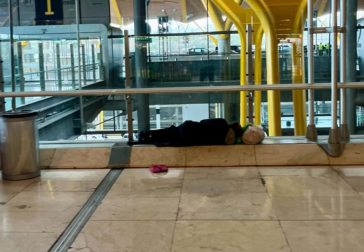 Un hombre duerme en una de las repisas de la terminal 4
