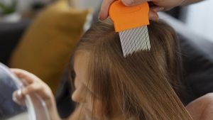 Una madre repasa el pelo de su hija con la liendrera de púas largas.
