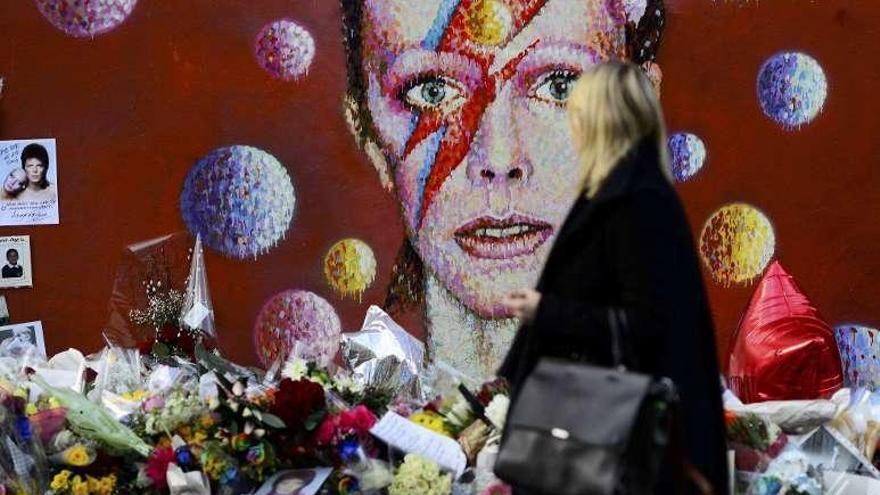 Una mujer deposita flores en homenaje a Bowie en Londres.
