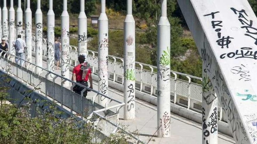 Las pintadas llenan todos los elementos de la pasarela peatonal de Outariz. // Brais Lorenzo