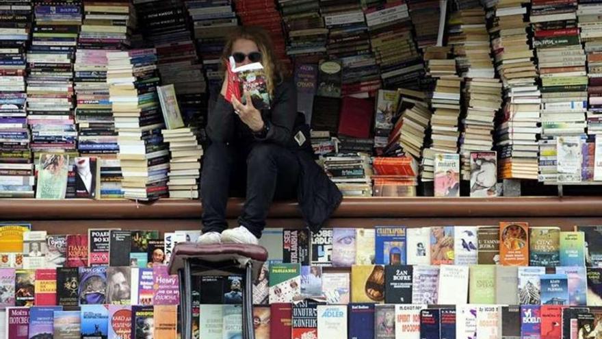 Una joven lee un libro en un quiosco callejero. reuters