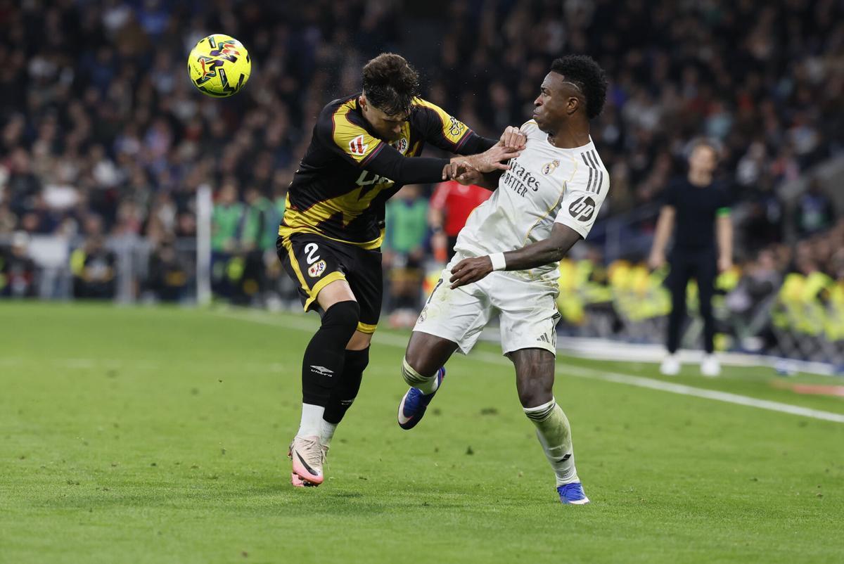 MADRID, 01/02/2026.- El delantero del Real Madrid Vinícius Jr (d) disputa un balón con el defensa del Rayo Vallecano Andrei Rațiu (i) durante el partido de LaLiga que enfrenta al Real Madrid y al Rayo Vallecano, este domingo, en el Santiago Bernabéu. EFE/ Ballesteros