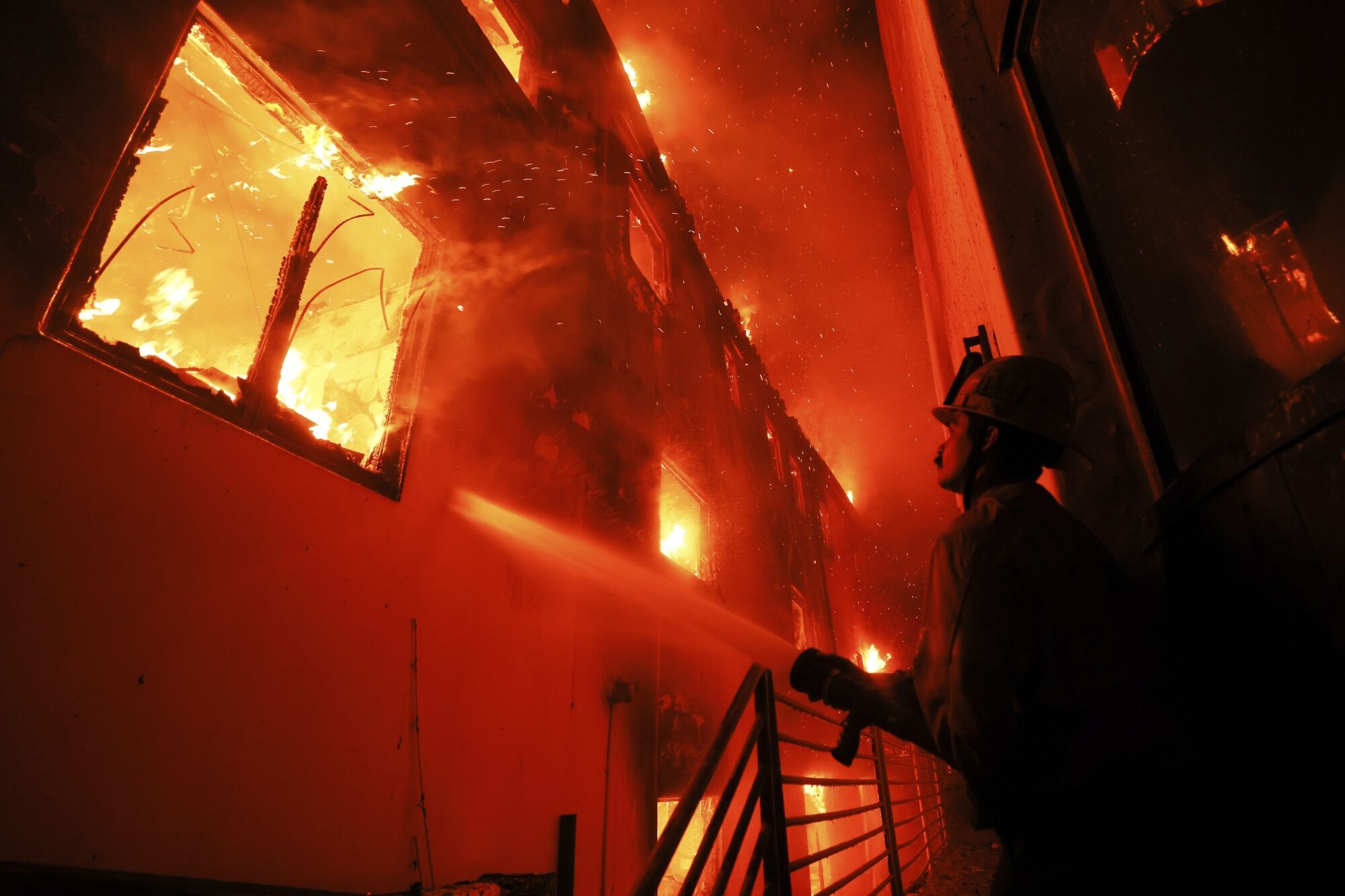 A firefighter works from a deck as the Palisades Fire burns a beachfront property Wednesday, Jan. 8, 2025, in Malibu, Calif. (AP Photo/Etienne Laurent) Associated Press / LaPresse Only italy and Spain. EDITORIAL USE ONLY/ONLY ITALY AND SPAIN