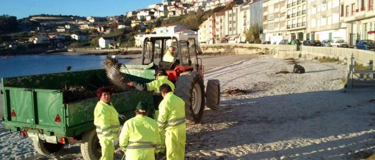 Trabajadores municipales limpiando la playa de Raxó. // Gustavo Santos