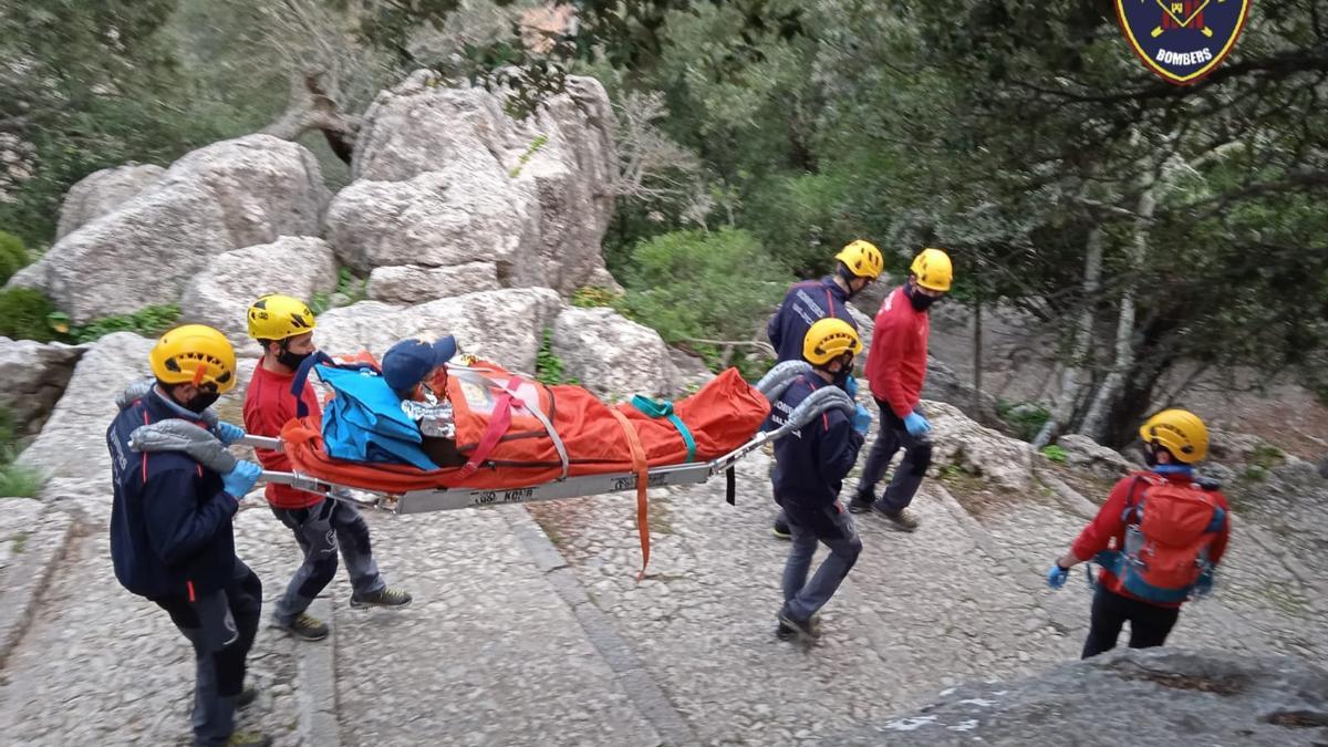 Varios bomberos trasladan a la víctima en camilla.