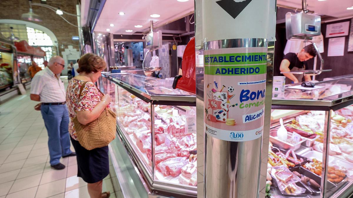 Dos personas observan el género en un puesto del Mercado Central.