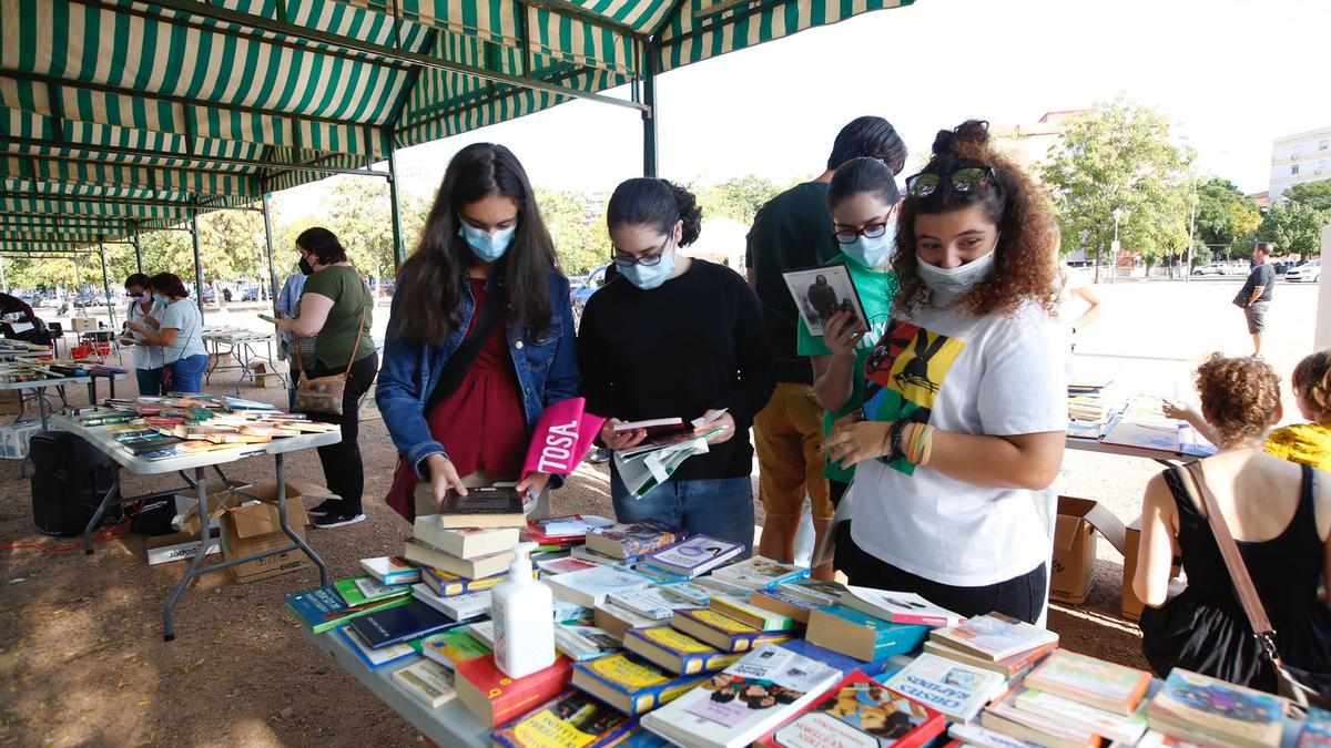 Varias jóvenes buscan en una de las mesas un libro que les pueda interesar.