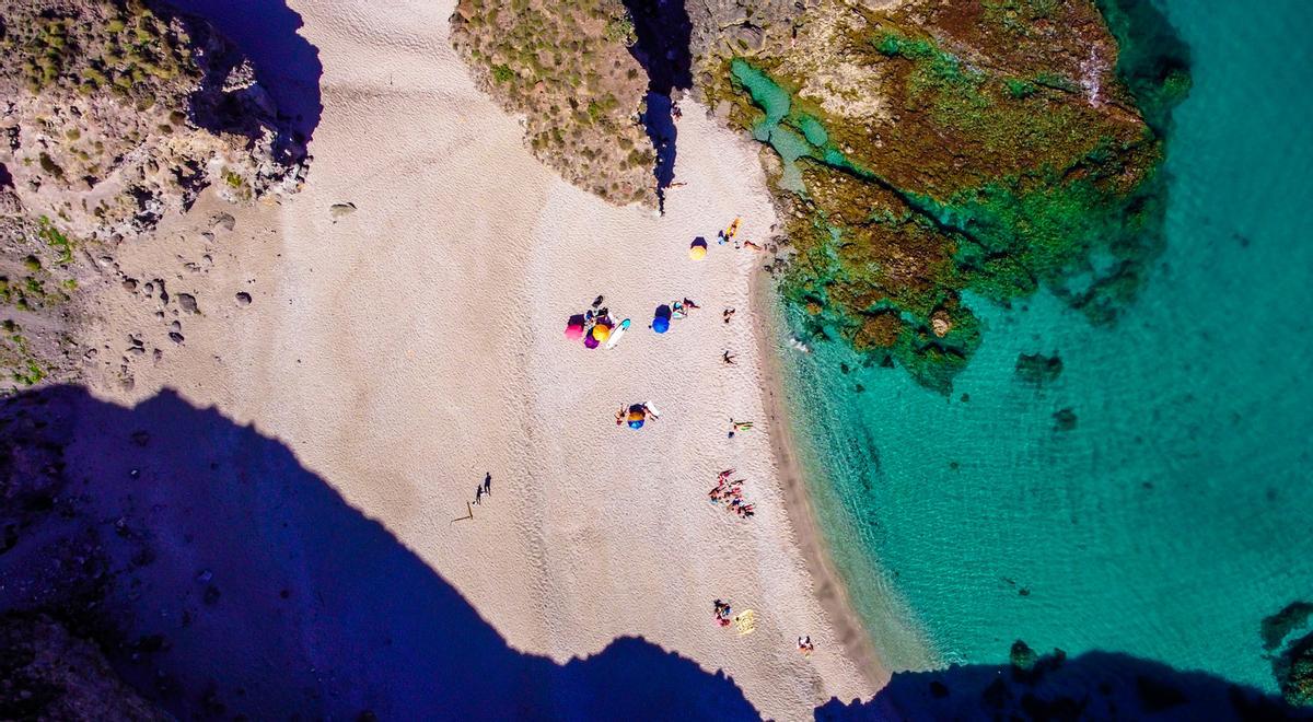 Vista aérea con drones de la orilla del mar, la costa, la vista panorámica de las personas en la playa virgen de Almería, llamada Playa de los Muertos