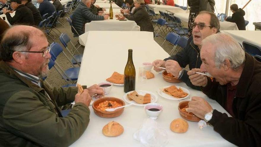 Algunos de los asistentes comiendo o recogiendo las raciones