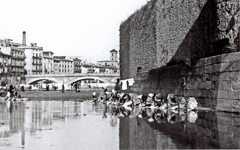 Les dones passaven hores fent la bugada a la llera del riu, en aquest cas a l’Onyar, fins que les va alliberar la rentadora mecànica. La imatge és de l’any 1900.