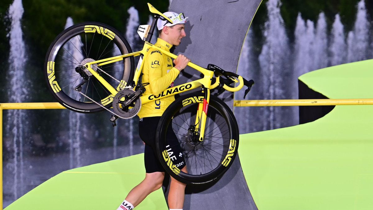 Tadej Pogacar, del equipo UAE, carga su bicicleta al podio de ganadores del Tour 2024