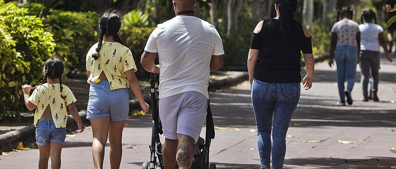 Unos padres pasean ayer con sus hijos por el parque de San Juan.