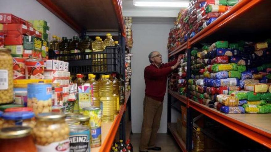 El director de Cáritas, ayer, colocando los alimentos en las estanterías. // Bernabé/Javier Lalín