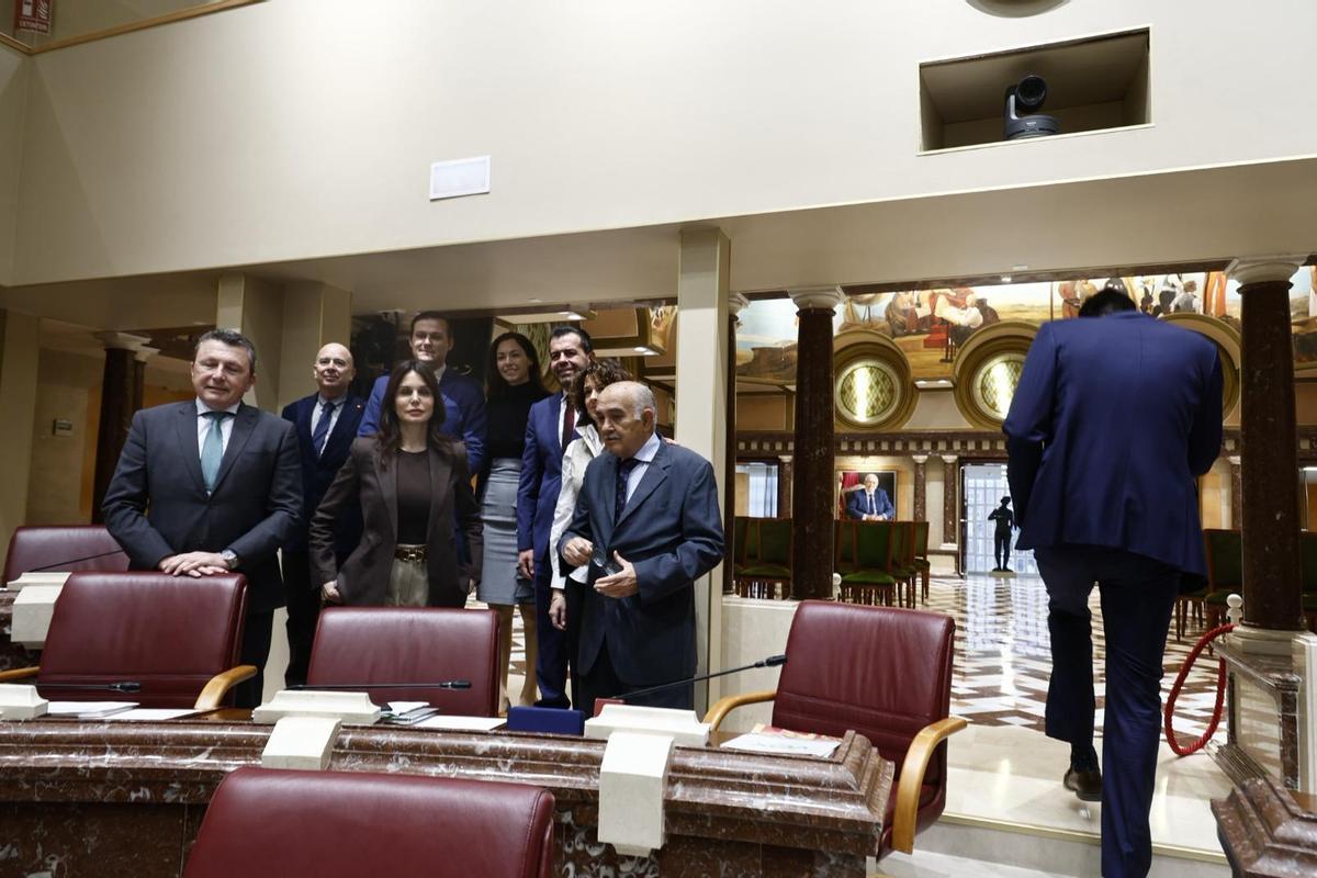 Los ocho diputados de Vox que acudieron a la reunión, en grupo haciéndose una foto mientras Antelo abandona el salón de Plenos al teléfono.