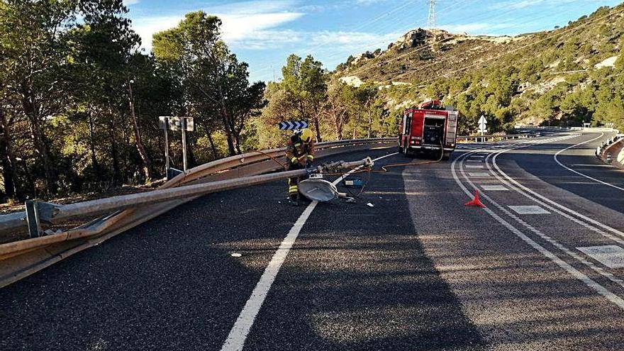 Els Bombers retiren un fanal caigut en una carretera.