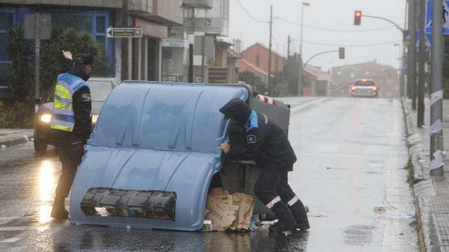 Policías de Bueu intentan levantar un contenedor. // S.A.