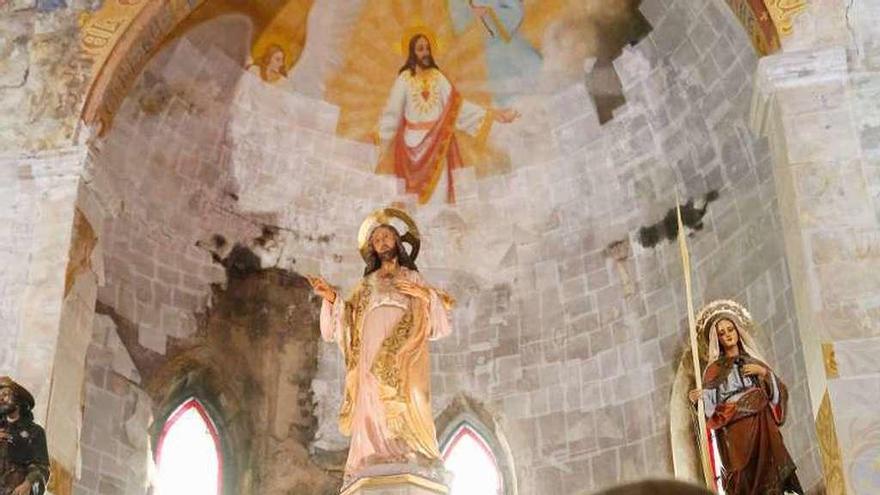 El sacerdote Francisco Alejandro del Rey señala las pinturas deterioradas en la iglesia de Villalegre.