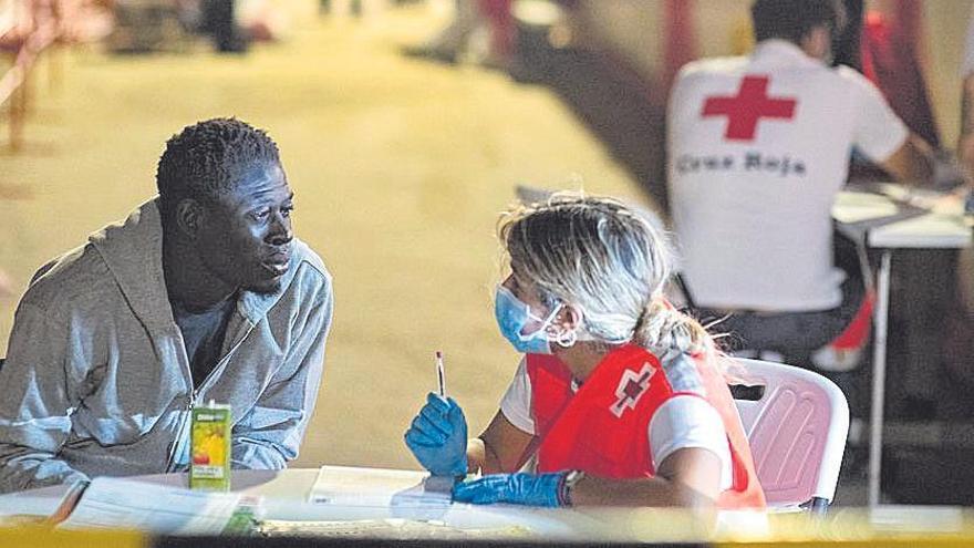 Uno de los 39 supervivientes de la lancha con una voluntaria de Cruz Roja al llegar al muelle de Gran Tarajal.