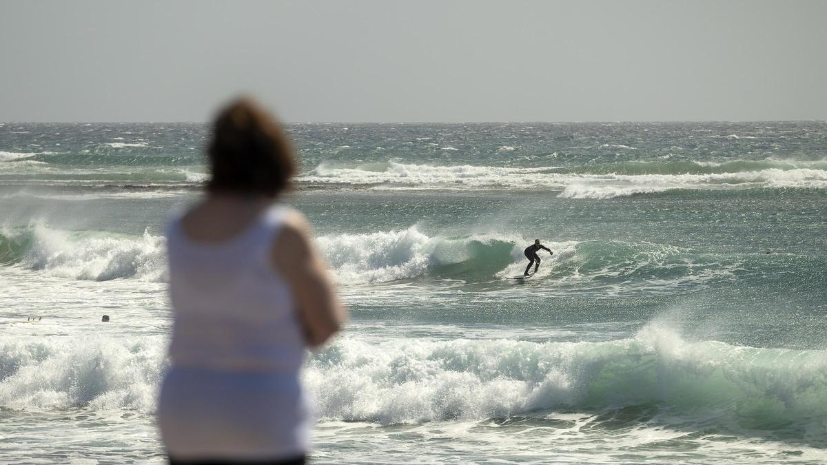 Una mujer observa a un surfista en Los Pocillos.