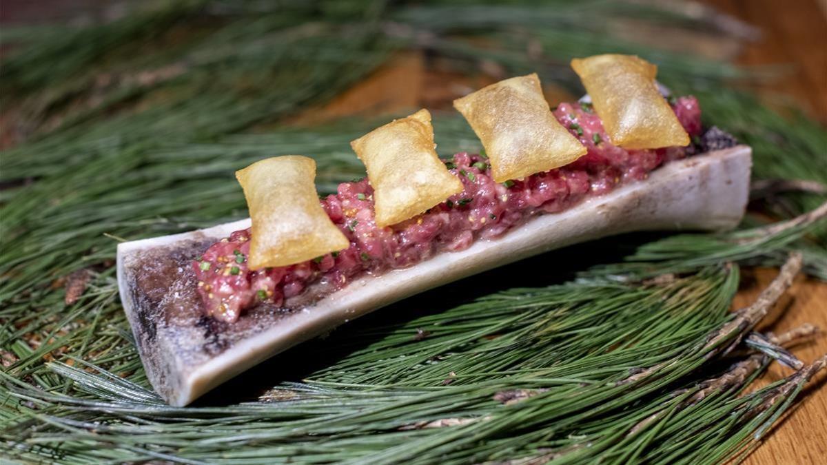 El 'steak tartar' con tuétano y patatas suflés, uno de los platos estrella de este restaurante del Raval de Barcelona.