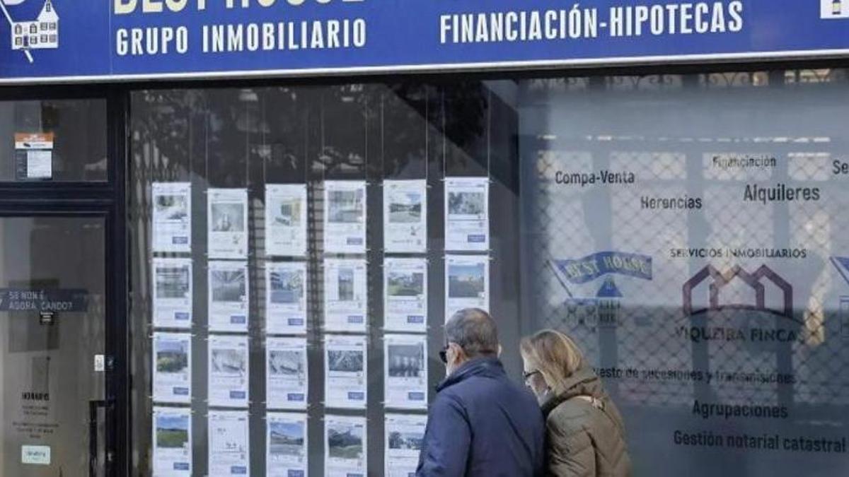 Una pareja pasa ante una agencia inmobiliaria en Santiago